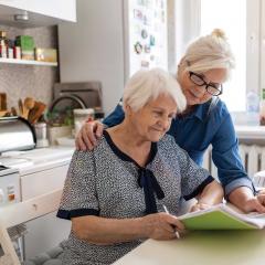 Woman helping elderly woman with paperwork